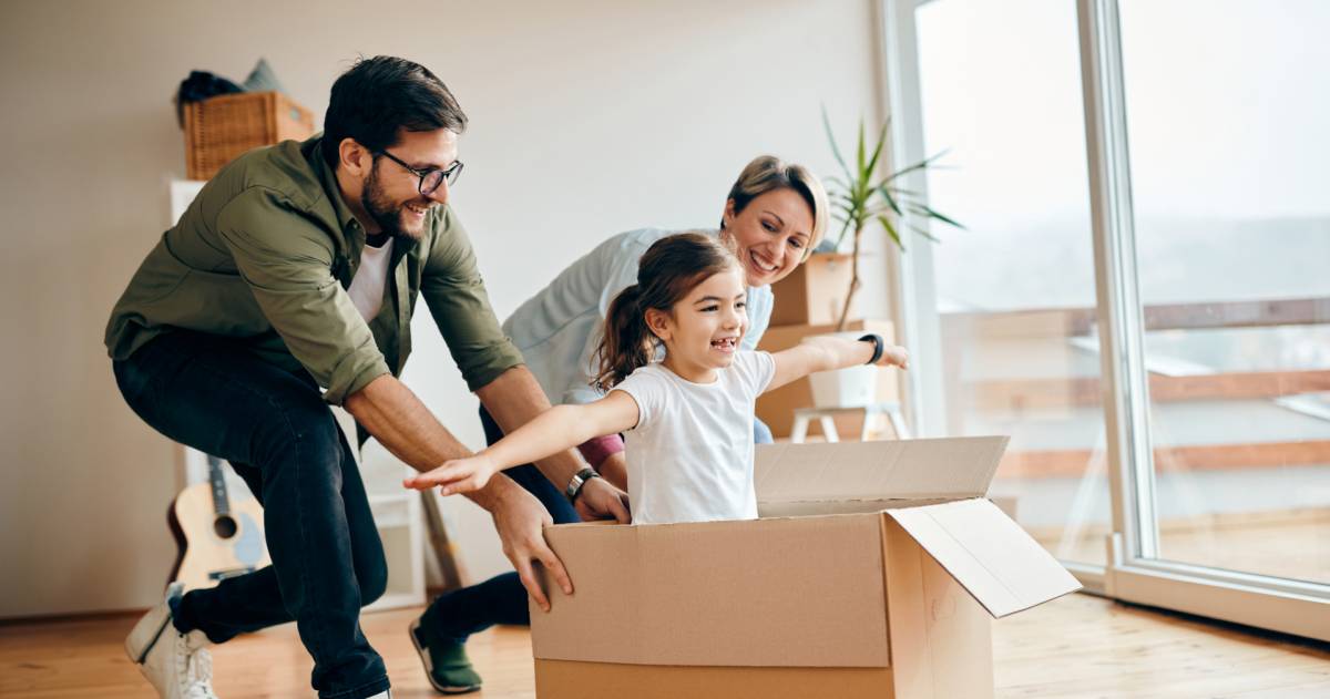 Gelukkige dochter die plezier heeft met haar ouders tijdens de verhuizing naar een nieuw huis