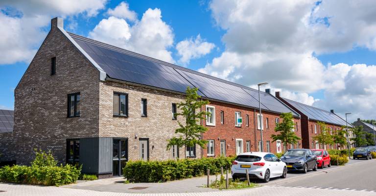 Rij nieuwe energiezuinige bakstenen rijtjeshuizen met het dak bedekt met zonnepanelen op een zonnige dag